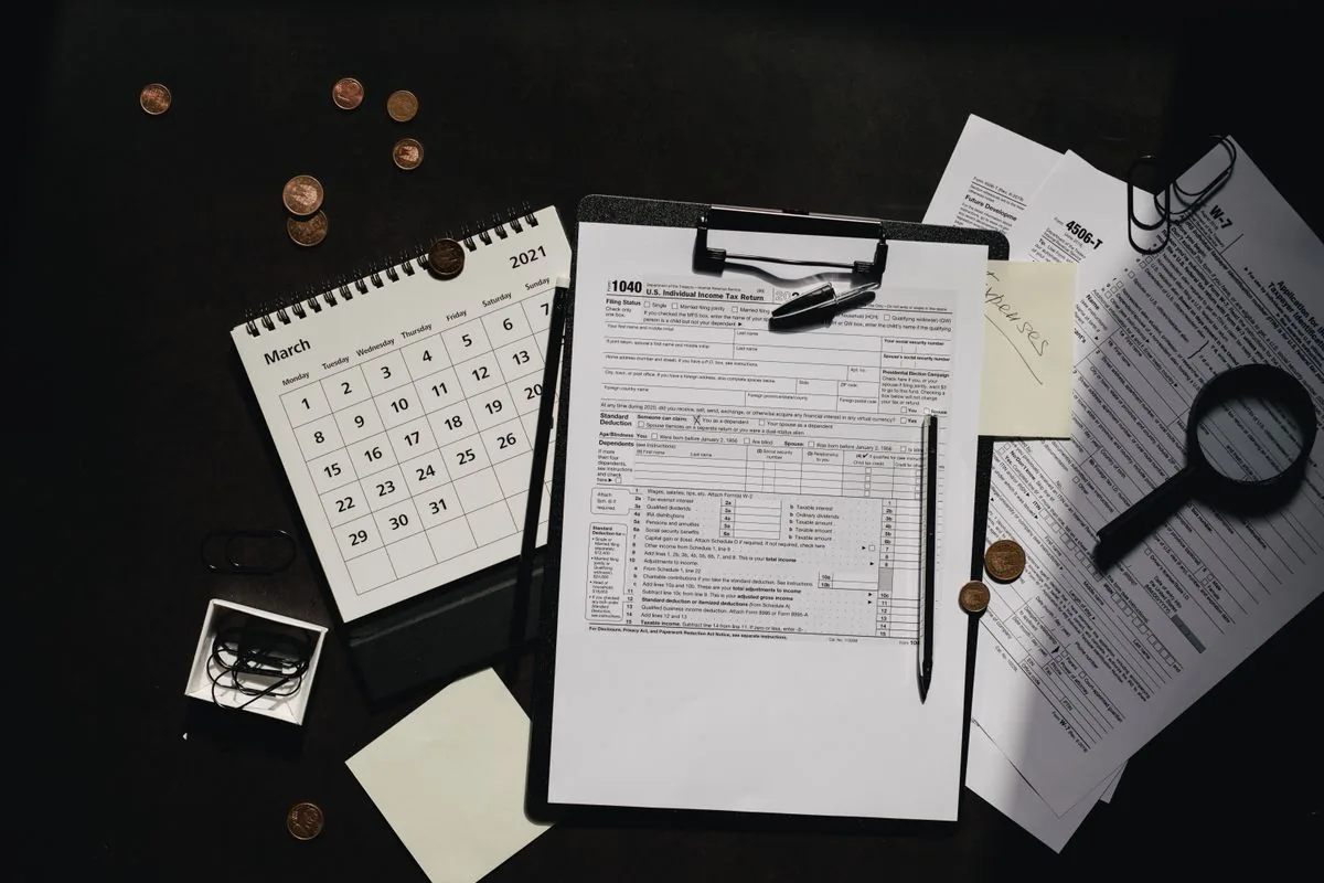 A tax form on a clipboard beside a desk calendar and a magnifying glass under low light.